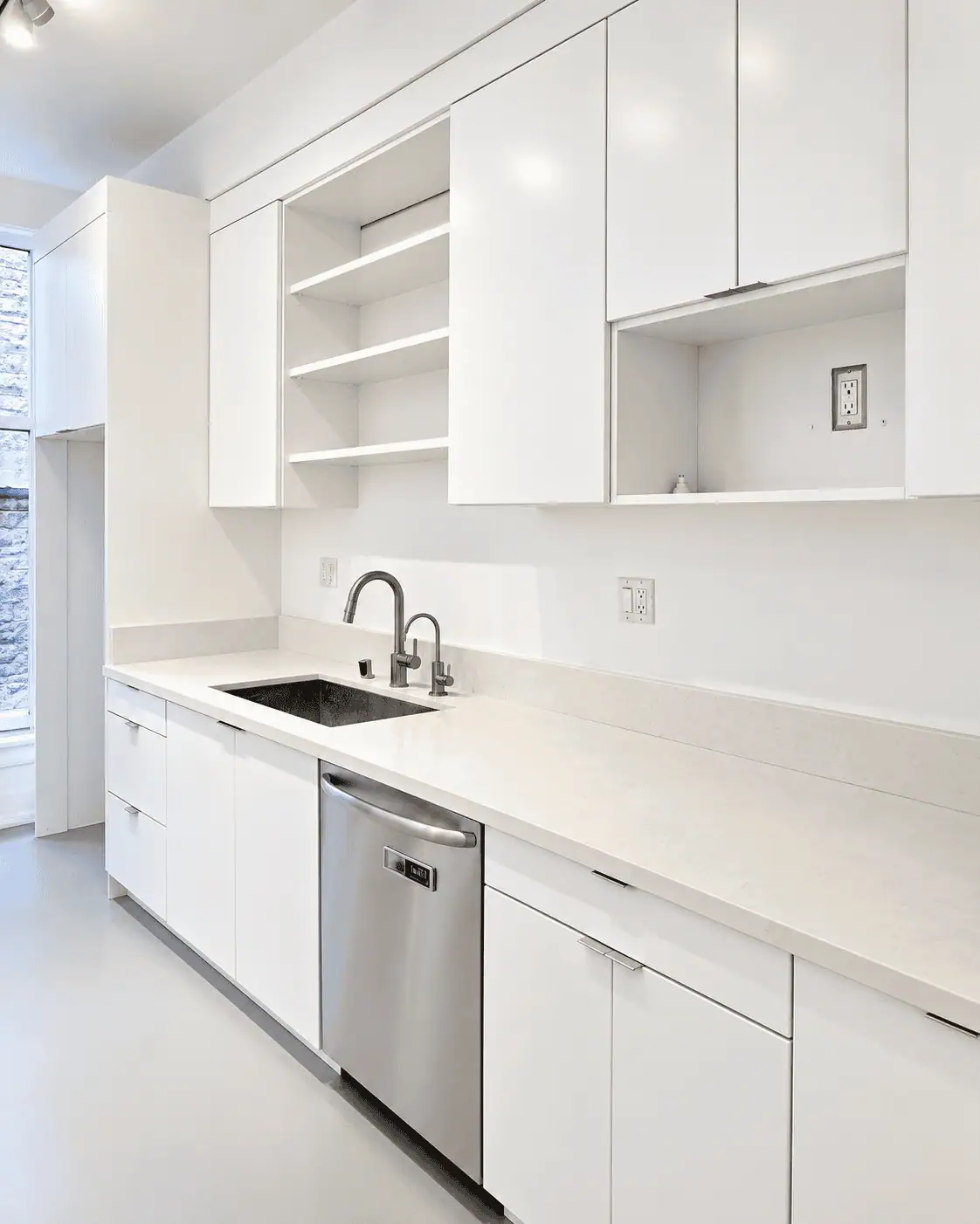 Contemporary white kitchen with sleek cabinets and stainless steel appliances.