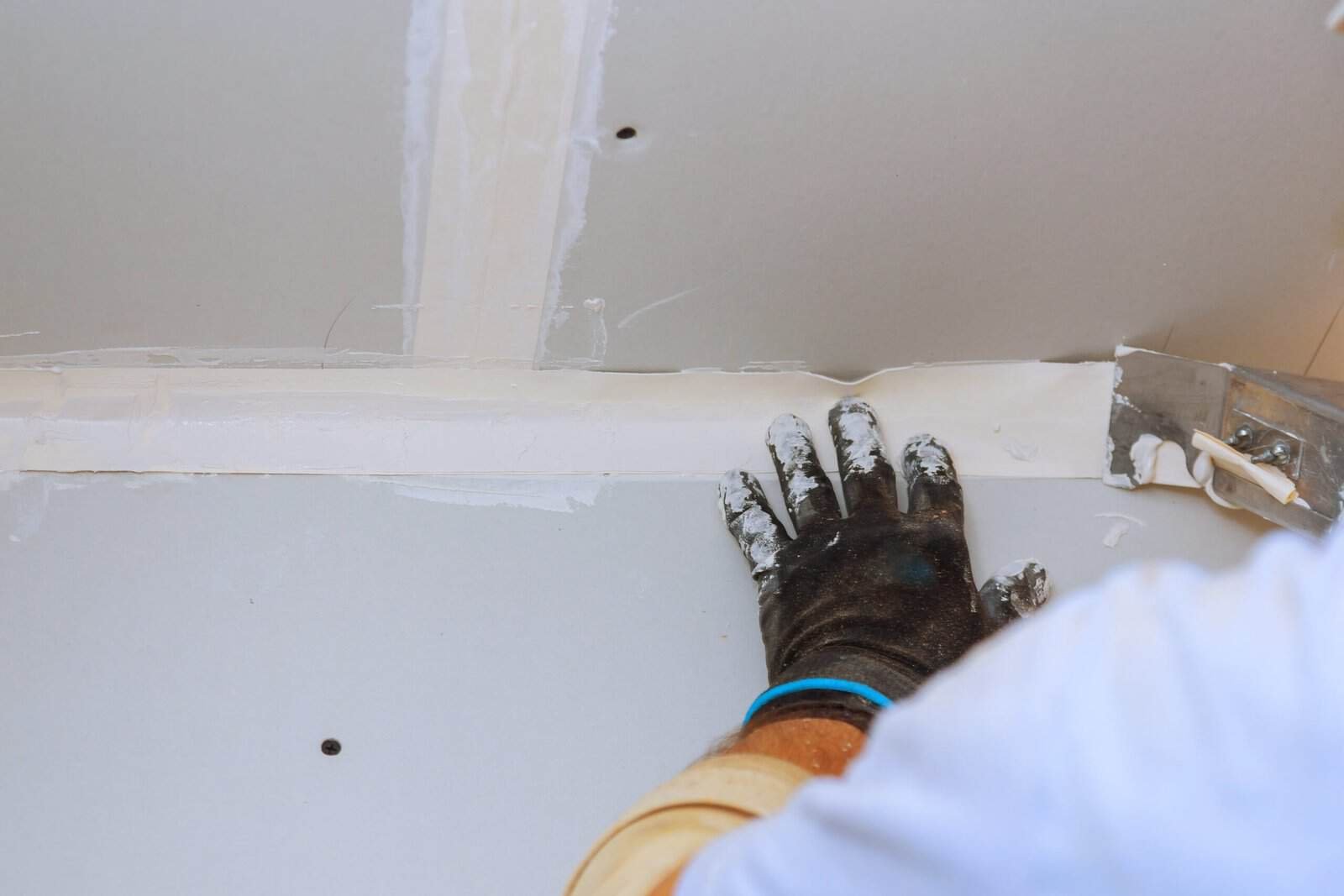 Worker installing drywall in new home construction site for quality finishing.